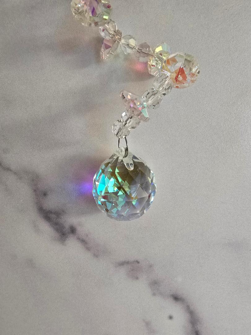 Close-up view of the Aurora Spiral suncatcher showing faceted AB-coated crystals and wirework, highlighting the shimmer and reflective texture.