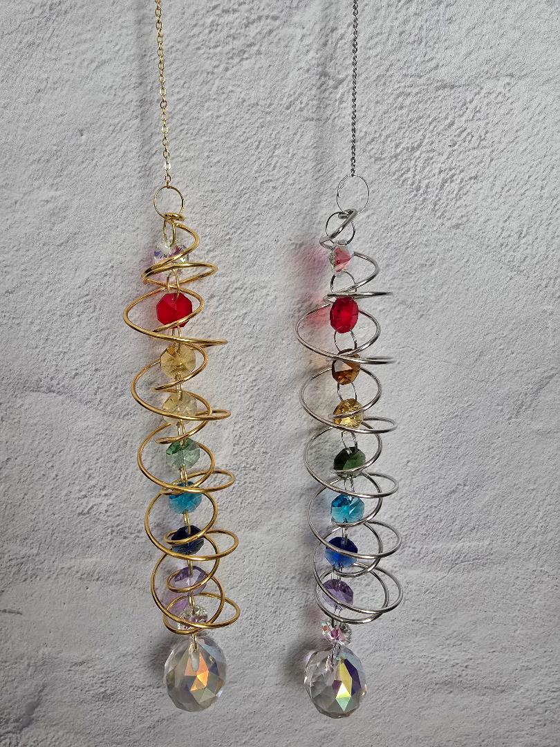 Side-by-side view of the gold and silver Chakra Spiral Suncatchers, each featuring rainbow chakra beads and a clear prism
