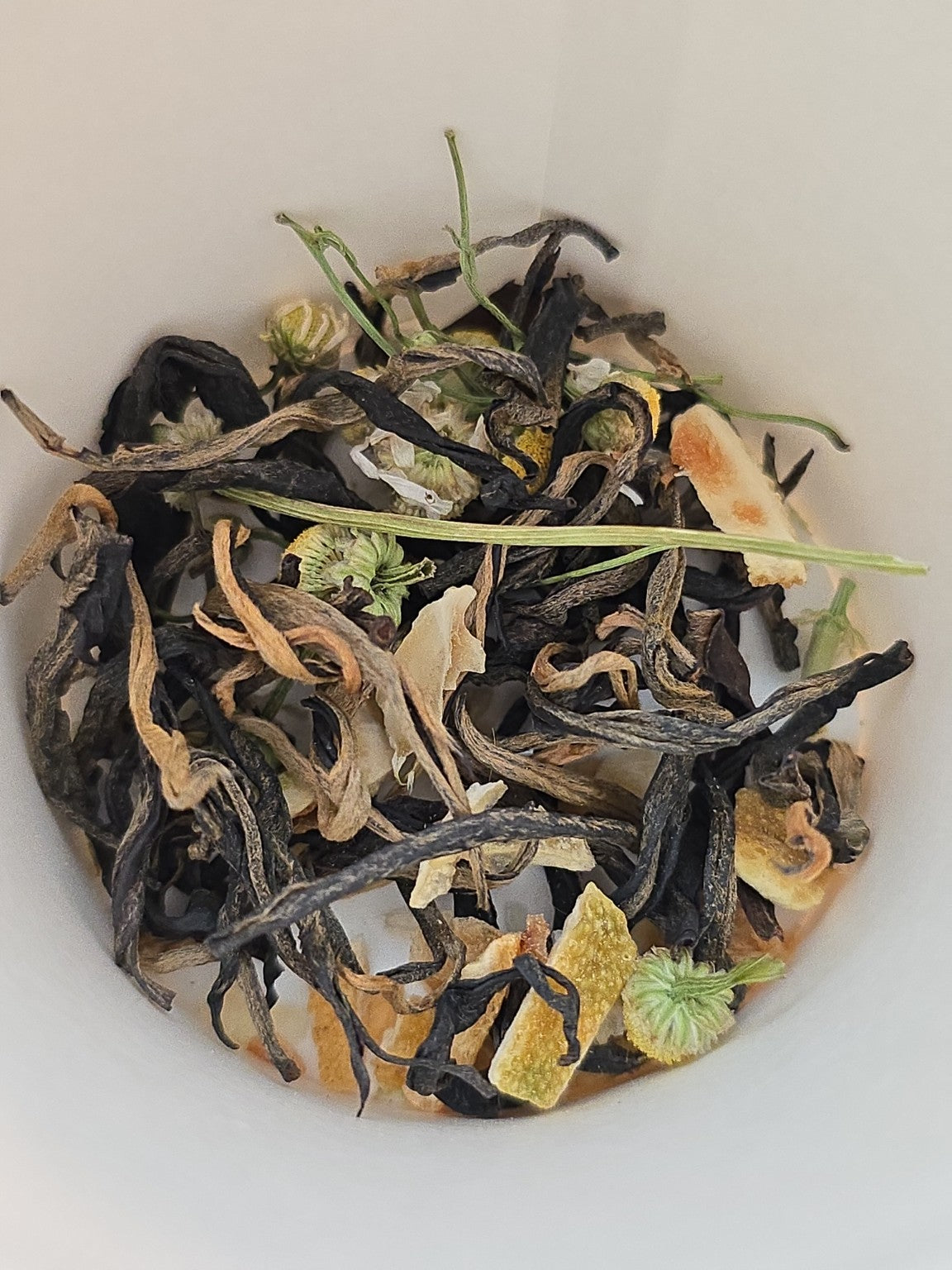 Custom tea blend featuring black tea, chamomile, and citrus botanicals inside a blending cup