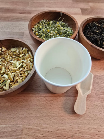 Organic loose leaf tea and botanical ingredients arranged around a blending cup for a tea blending experience