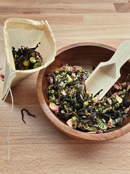 Handcrafted tea blend being scooped into a tea bag during a tea blending gathering activity
