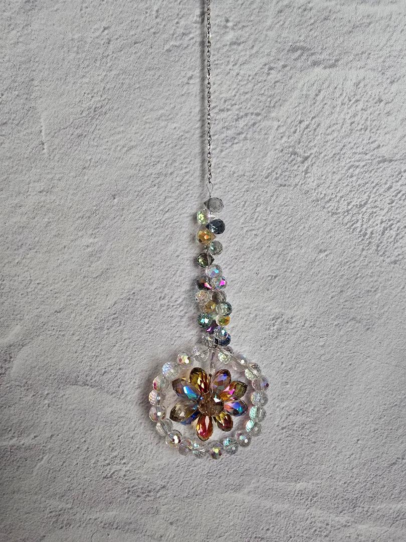 Floral Radiance Suncatcher with a golden-yellow faceted crystal flower framed by clear crystals and an iridescent beaded stem