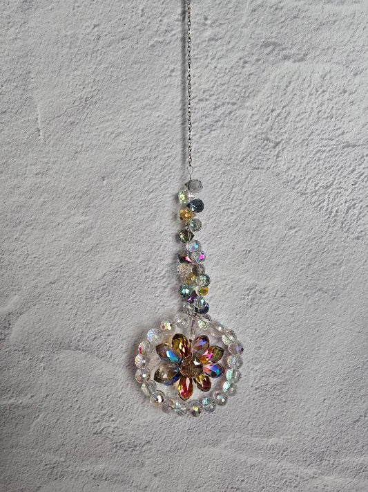 Floral Radiance Suncatcher with a golden-yellow faceted crystal flower framed by clear crystals and an iridescent beaded stem