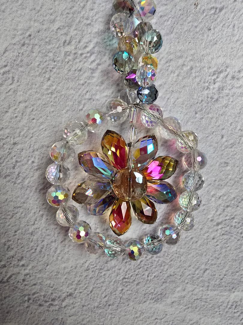 Close-up of the Golden Dawn Blossom suncatcher showing the golden faceted petals, central round crystal, and surrounding clear and iridescent beads