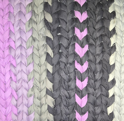 Close-up of a hand-twined cotton rug showing subtle heart-shaped accents woven into black and violet sections.