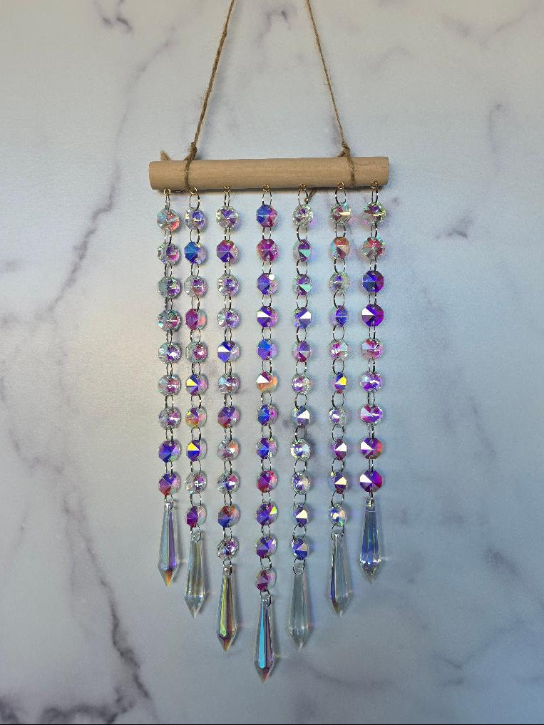 Full-length view of the Aurora Crystal Suncatcher showing all crystal strands and prism pendants with soft rainbow reflections on a marble background