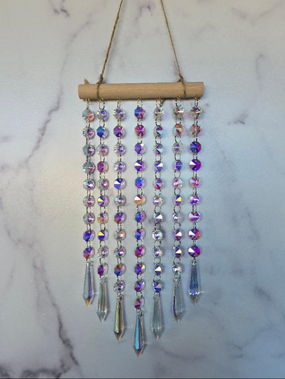 Full-length view of the Aurora Crystal Suncatcher showing all crystal strands and prism pendants with soft rainbow reflections on a marble background