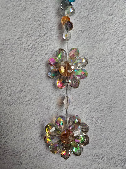 Close-up of the Twin Petal Cascade suncatcher showing both layered iridescent crystal flowers and the shimmering multicolor accent beads