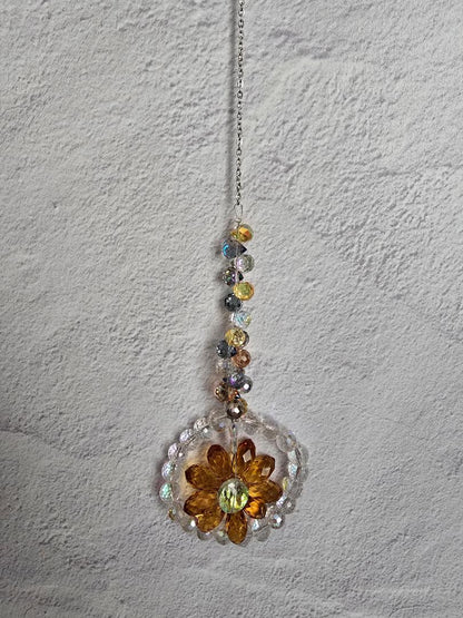 Floral Radiance Suncatcher with a warm amber-gold faceted crystal flower surrounded by clear crystals and a golden-tone iridescent beaded stem