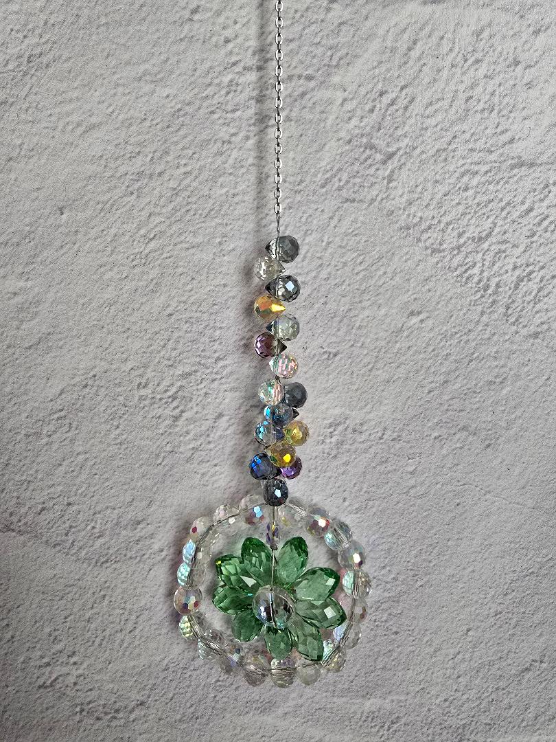Floral Radiance Suncatcher with a green faceted crystal flower ringed by clear crystals and a cool-tone iridescent beaded stem