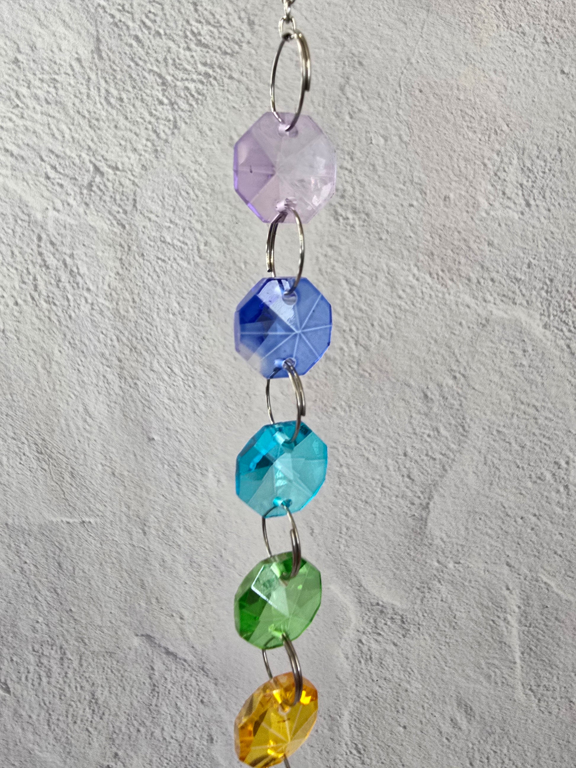 Close-up of the upper section of the Sevenfold Halo suncatcher showing faceted glass crystals arranged in a rainbow progression.