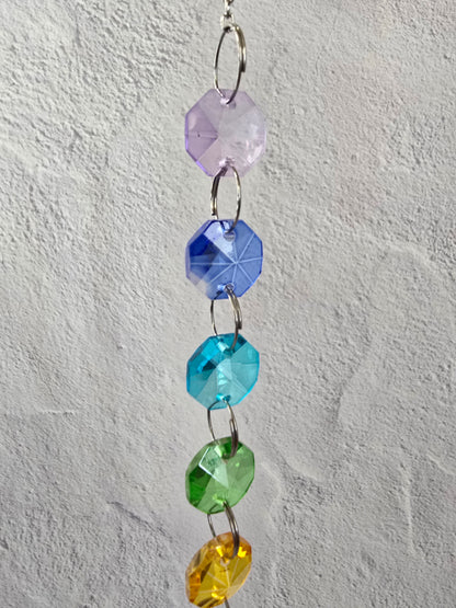 Close-up of the upper section of the Sevenfold Halo suncatcher showing faceted glass crystals arranged in a rainbow progression.