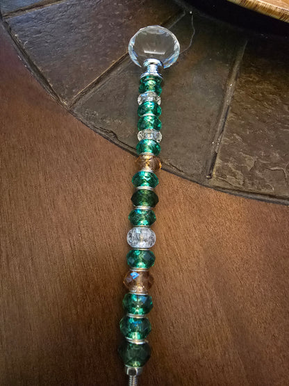 Completed green beaded garden stake with faceted crystal-style topper displayed on a wooden tabletop.