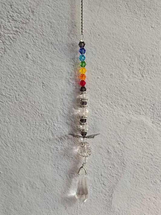 Mini prism suncatcher with rainbow crystal beads, wing charm, and a clear prism drop hanging against a textured white wall.