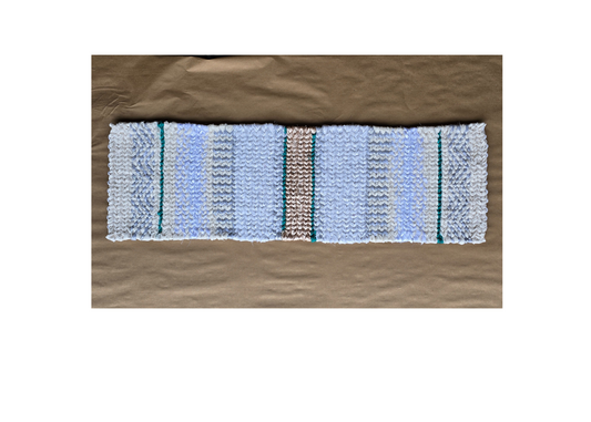 Hand-twined Winter Glow table runner in cool white and silver tones, displayed on kraft paper background