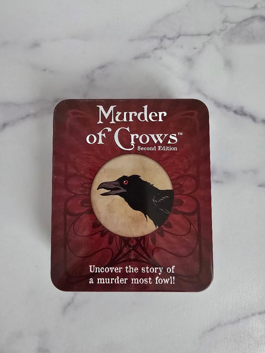 Murder of Crows card game tin shown from above on a marble background