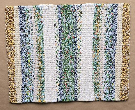 Hand-woven cotton rug named Savanna Bloom, featuring a rectangular striped pattern in white, various greens, multi-colored floral fabric, and gold shimmer accents. The rug is approximately 31 by 24 inches.